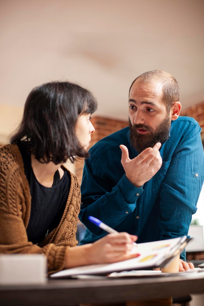 Cliente e grafico discutono una bozza al tavolo